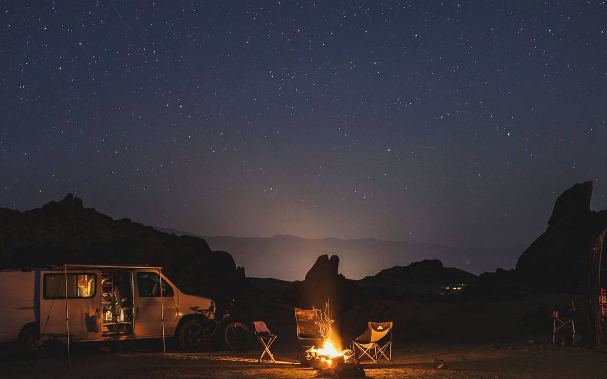 Campfire and camping chairs under a starry desert sky